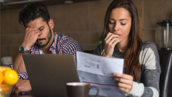 Photo of a couple looking stressed out while viewing their electricity bill.